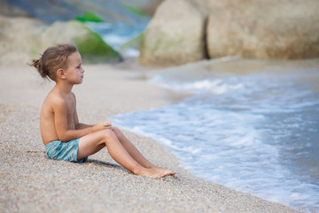 Fototapeta na wymiar boy sitting on the sand by the sea