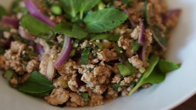Homemade healthy Thai food Spicy Minced Pork Salad or called Larb Moo in white plate on brown table