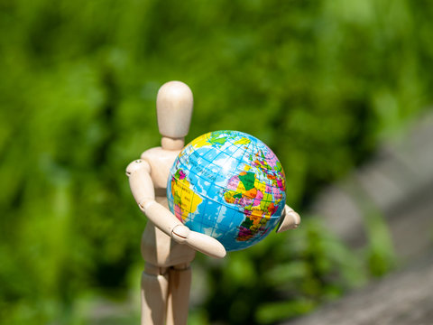 A wooden mannequin with a world ball in his arms. Ecology concept, globalization