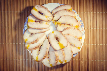 Half smoked fish on a plate lined with slices on a wooden background