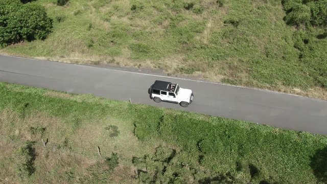 Aerial, car drives on Hawaiian road