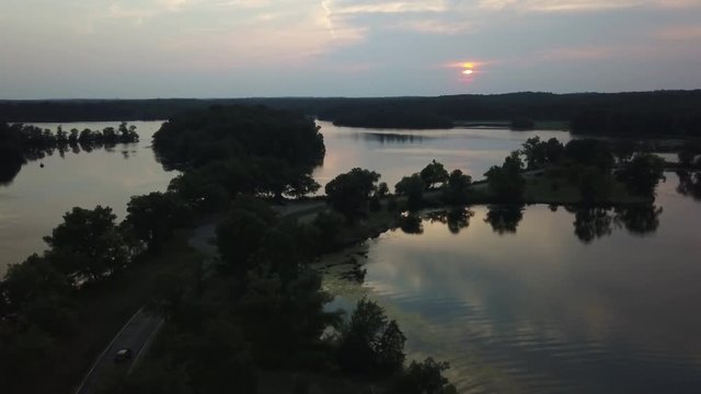 Aerial, car drives through lake in Milford, Michigan at sunset