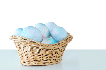 Easter yellow eggs in a straw basket. On the table. White isolate Blank background