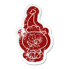 cheerful sitting pig cartoon distressed sticker of a wearing santa hat