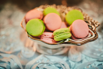 Colorful macarons stand in round transparent weight as part of candy bar sweet table