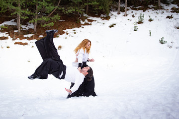 Aikido in the snow. Woman and man fighting in the forest