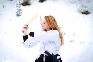 Aikido in the snow. Woman and man fighting in the forest