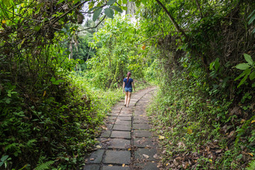 A young girl is on a stone path in the jungle of Ubud.