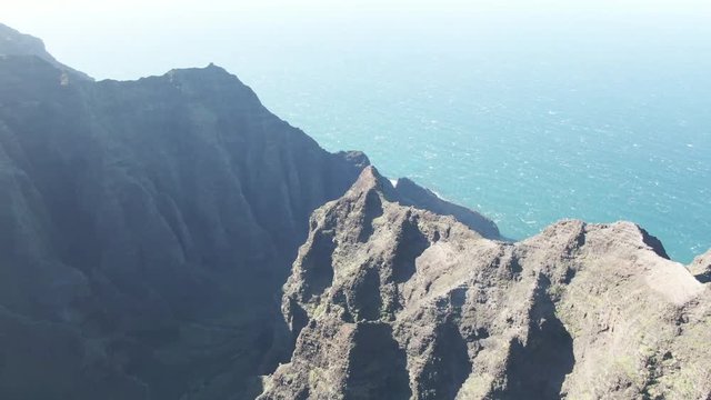 Top of mountains overlook water in Hawaiian state park, aerial view
