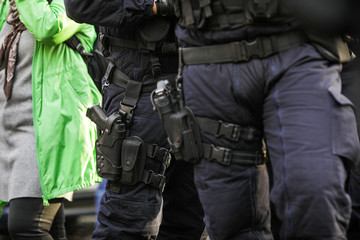 Details of the security kit of a riot police officer, including handcuffs, 9mm handgun, radio station and baton