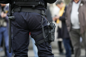 Details of the security kit of a riot police officer, including handcuffs, 9mm handgun, radio...