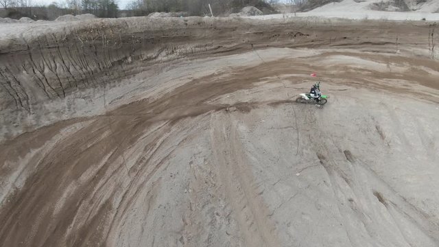 Aerial, person rides dirt bike on track