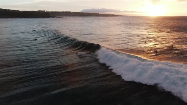 Aerial, surfer rides wave at sunset in Honokahua Bay, Hawaii