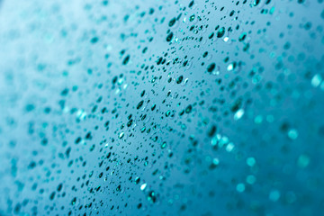 Fototapeta na wymiar Drops of water on a bluish-green metallic surface