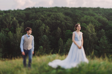 Romantic and happy caucasian couple in stylish clothes hugging on the background of beautiful nature. Love, relationships, romance, happiness concept. Man and woman walking outdoors together.