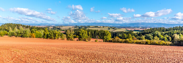 Typical red soil of countryside around Nova Paka. Agricultural Landscape with Giant Mountains on the background. Czech Republic - obrazy, fototapety, plakaty