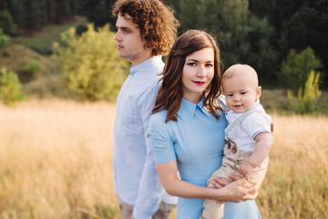 Fototapeta premium Young happy caucasian couple with little baby boy. Parents and son walking and having fun together. Mother and father playing with toddler outdoors. Family, parenthood, childhood, happiness concept.