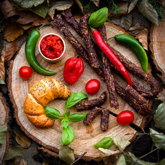 Smoked sausage on wooden tree trunk