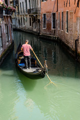 Fototapeta na wymiar Italy, Venice, Gondolier navigating a gondola near San Moise on a canal