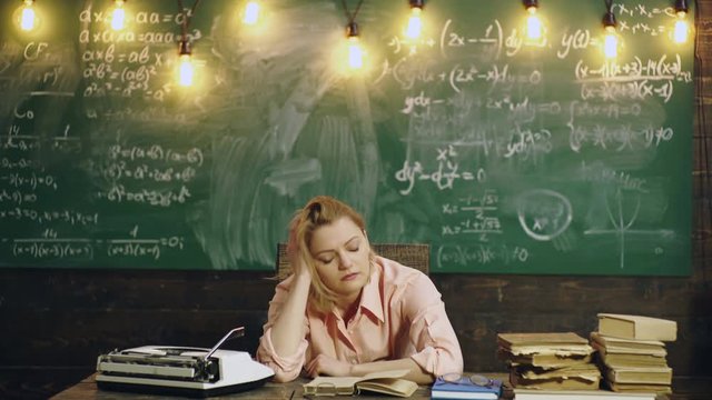 Teacher reads a book in class. Female teacher falls asleep reading a book in class. Learning concept. Teacher in classroom. Teacher and student. Back to school.