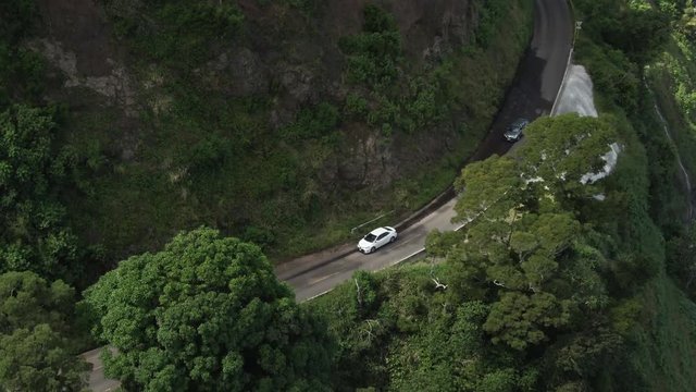 Cars drive along cliff on the Road to Hana in Maui, Hawaii, aerial