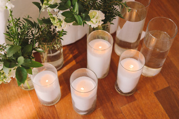 Coziness and style. Modern event design. Table setting at wedding reception. Floral compositions with beautiful flowers and greenery, candles, laying and plates on decorated table.