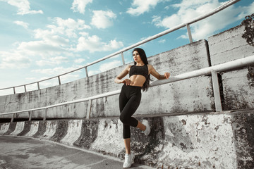 Fototapeta na wymiar Portrait of beautiful brunette. Sexy girl rest after running. Female fitness model working out outdoor in city. Young woman jogger athlete training on road. Concept of healthy lifestyle.