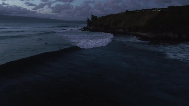 Aerial, surfers in Honokahua Bay, Hawaii at dusk