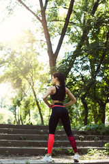 Athletic girl running in the nature. Female jogging on bridge at the park. Young woman stretching before run. Fitness model working out outdoor. Concept of healthy lifestyle.