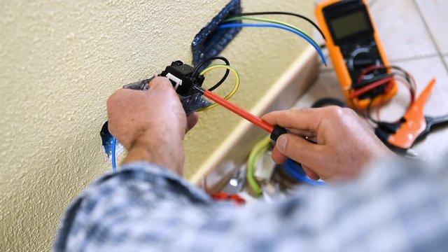Electrician technician worker inserts and fixes the cables in the electrical socket of a residential electrical system. Construction industry. Building. Footage. 
