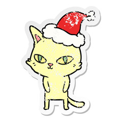 distressed sticker cartoon of a cat with bright eyes wearing santa hat