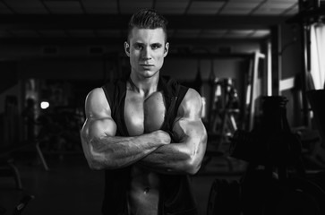 Fototapeta na wymiar Muscular model sports young man exercising in gym. Black and white portrait of strong muscle. Fitness trainer. Sport workout bodybuilding motivation concept. Sexy torso.