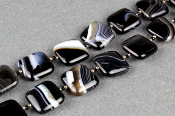Beads of natural stones black agate on a gray background.
