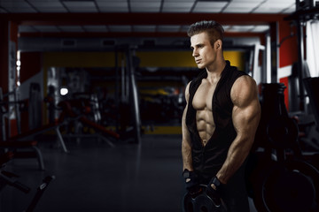 Muscular model young man exercising in gym. Portrait of sporty strong muscle. Fitness trainer. Sport workout bodybuilding motivation concept. Sexy naked torso, six pack abs. Male flexing his muscles.
