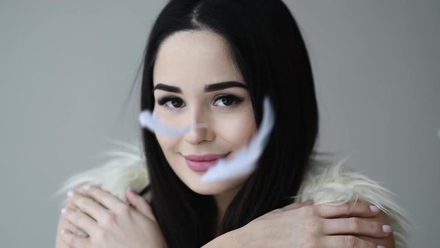 Close up portrait of woman open her eye with feathers falling down makeup and long eyelashes and free text space