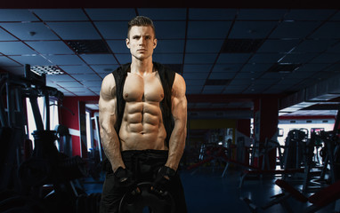 Naklejka premium Muscular model sports young man exercising in gym. Portrait of sporty healthy strong muscle. Fitness trainer. Sport workout bodybuilding motivation concept. Sexy torso.
