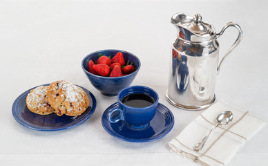 Breakfast of Scones on a Dark Blue Plate and Bowl of Fresh Strawberries with Coffee and a Silver...