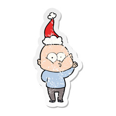 distressed sticker cartoon of a bald man staring wearing santa hat