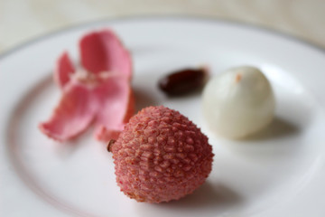 Lychee, peeled and unpeeled on a plate