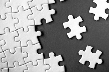 Close-up view of white jigsaw puzzle pieces on grey background