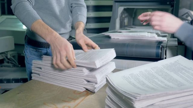 Print office workers stack paper, close up.