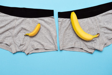 baby banana compare size with big banana on male panties on blue background.