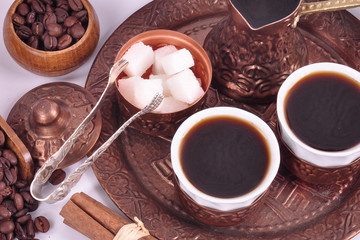 Coffee in copper coasters with accessories for coffee-drinking on a white background.