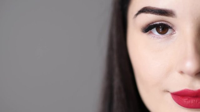 Closeup portrait of young woman open her eye with makeup and long eyelashes and free text space on gray background