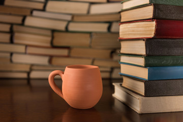 cup and many books on a wooden table