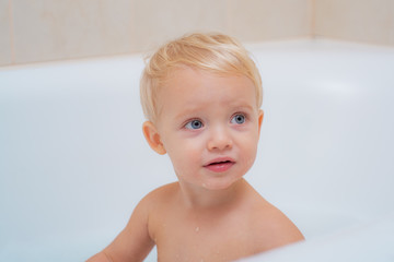Little baby washing with a bubbles. Happy toddler baby taking a bath playing with mother and foam.