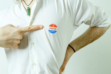 Man pointing to an I Voted Today sticker on his chest.