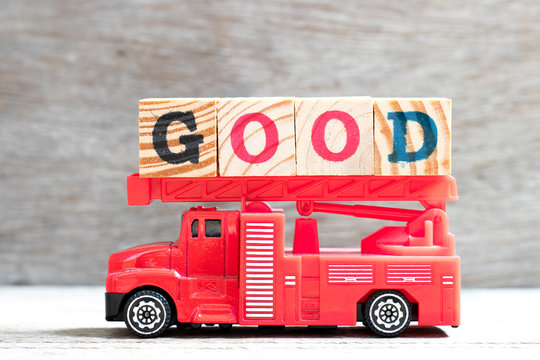 Toy fire ladder truck hold letter block in word good on wood background