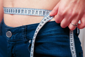 Woman measuring her waistline as symbol of diet and healthy lifestyle.