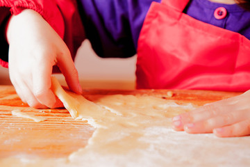 Close up view of baker are working. Hands of cute little child girl chef preparing dough on wooden table. Food and сooking process concept.